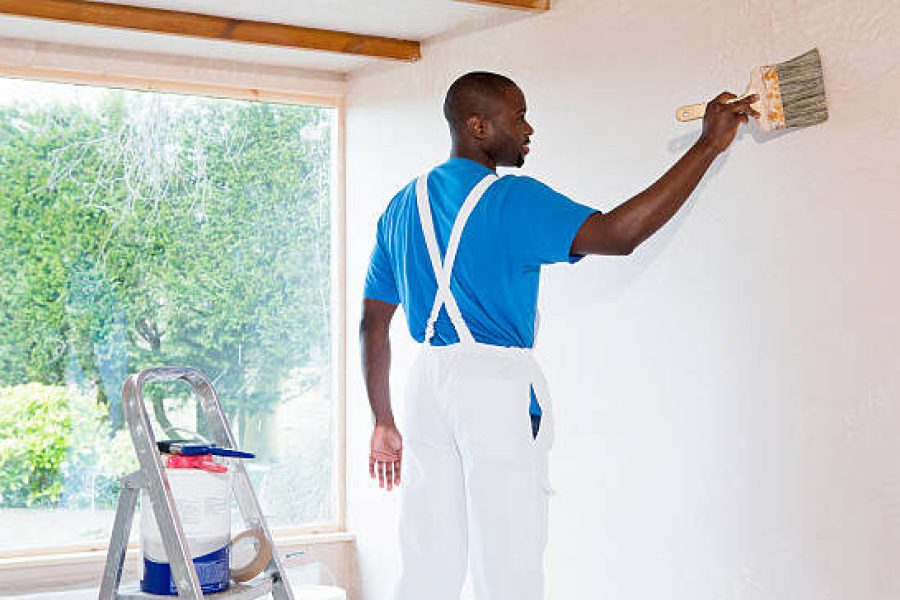 Shot from behind of a male painter working on a new home.